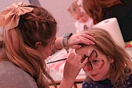 A child getting their face painted like a reindeer