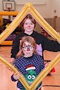 two children holding a frame up and getting their picture taken with it