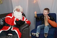 A child sitting with Santa and ringing his bell