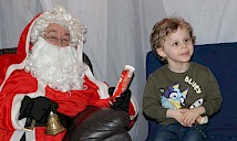 A child smiling getting his photo taken with santa
